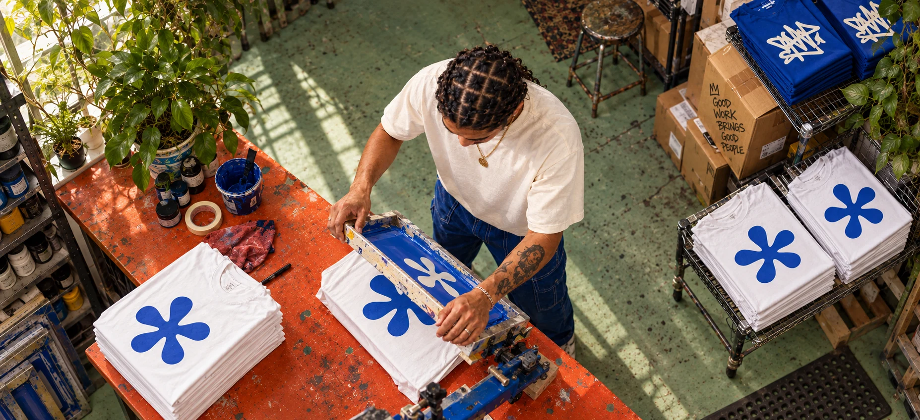 Concept photograph of a printmaker organising a shirt-printing station in an orange and mint studio.